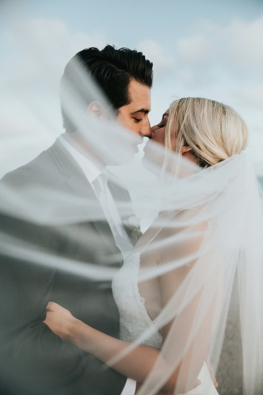 A couple sharing a kiss beneath the veil